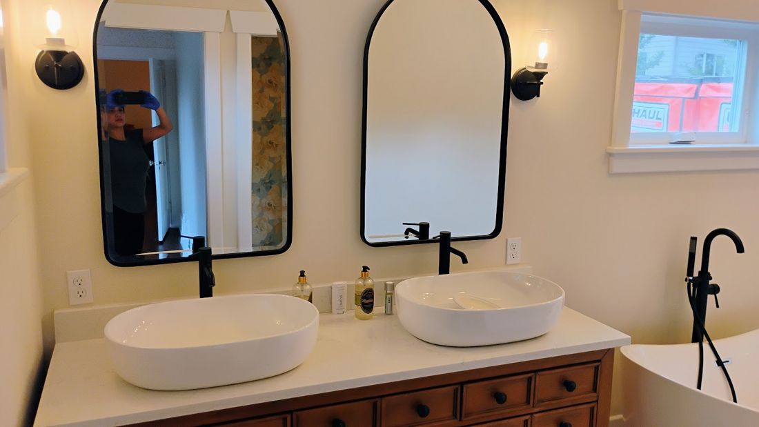 Double vessel-sink vanity with black fixtures and arched mirrors
